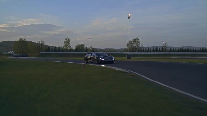 A car is driving on a road at dusk
