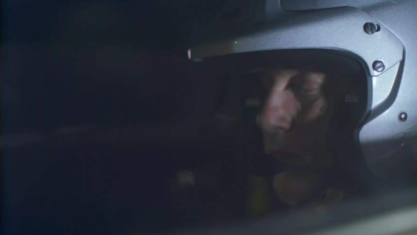 Man wearing a helmet and mic sitting inside of a moving vehicle