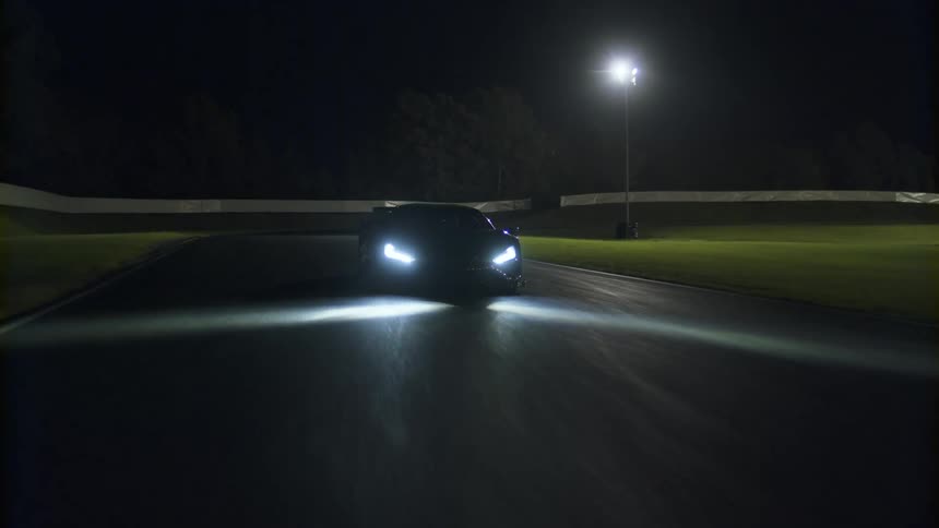 A sports car driving fast on a paved road at night