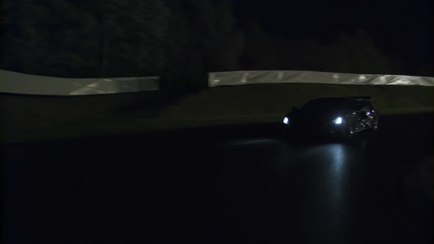 A car is driving on a road at night