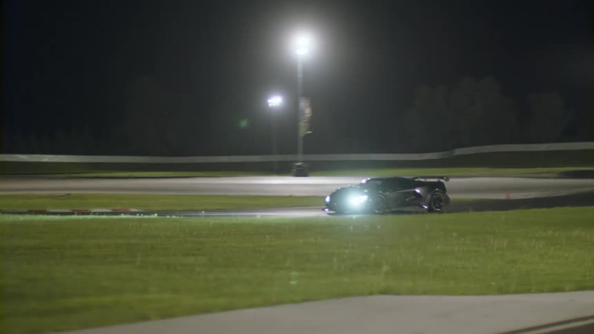 A black sports car is driving on a race track at night