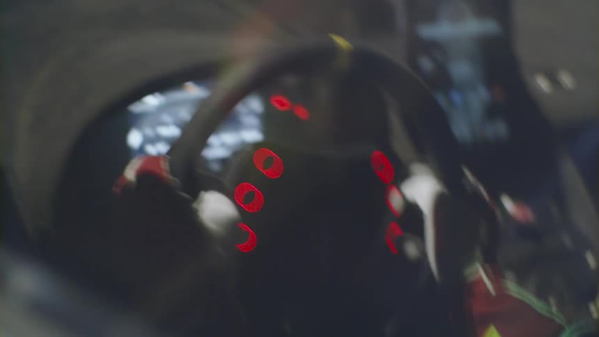Car interior with steering wheel console gloves on hands gripping wheel and red lights