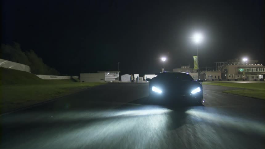 A sports car driving on a road with buildings streetlights and the sky in the background