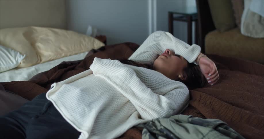 A dispirited woman laying on a bed