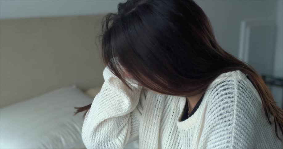 A woman sitting on a bed crying