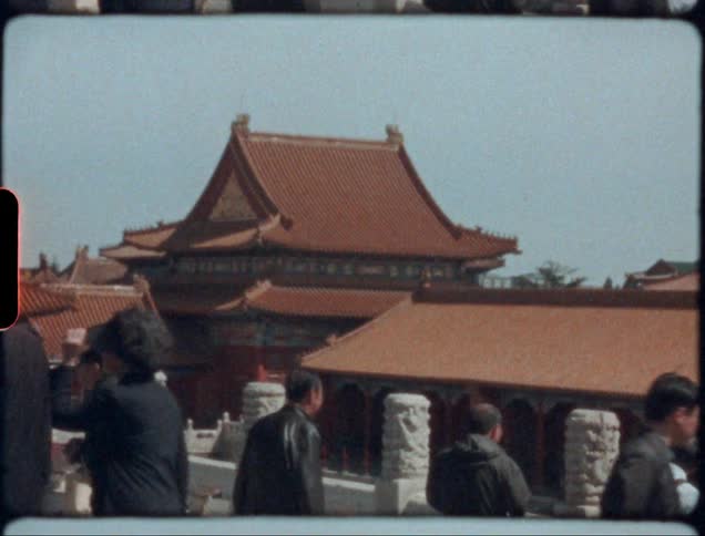 Men and women walk along a crowded street in front of a pagoda