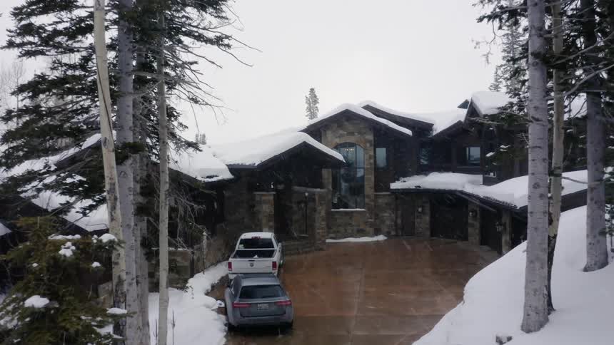 Snow covers a house next to many trees