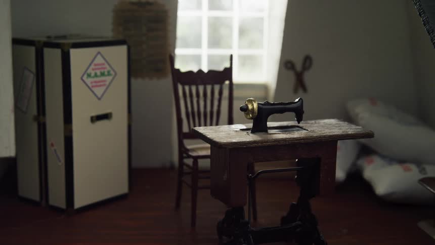A dollhouse with a toy sewing machine and chair