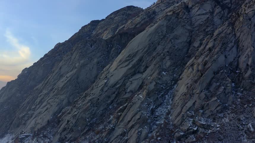 Cliff side of a mountain with a sun setting behind it