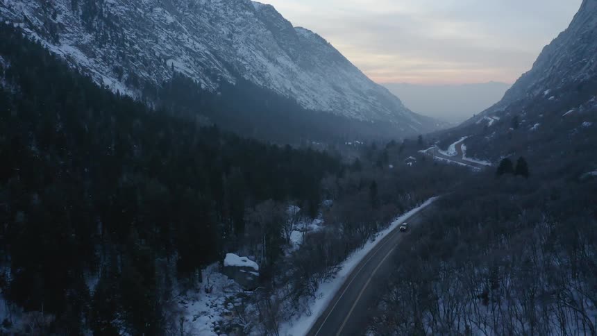 Aerial view of a car driving by the mountains in winter