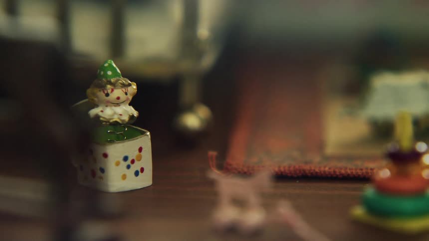 A ceramic jack in the box and stacking game sit on the floor of a bedroom next to a rug