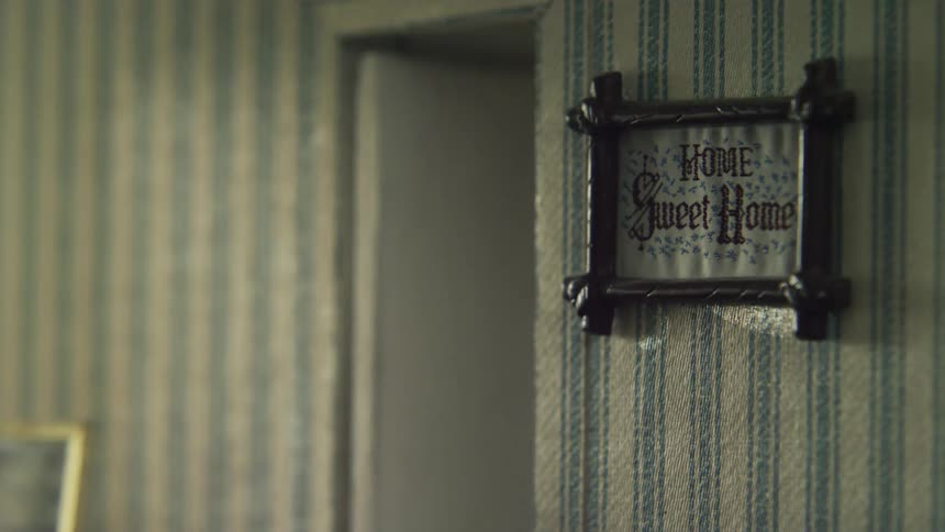 A sign that reads home sweet home hangs on the wall of a room next to an open door