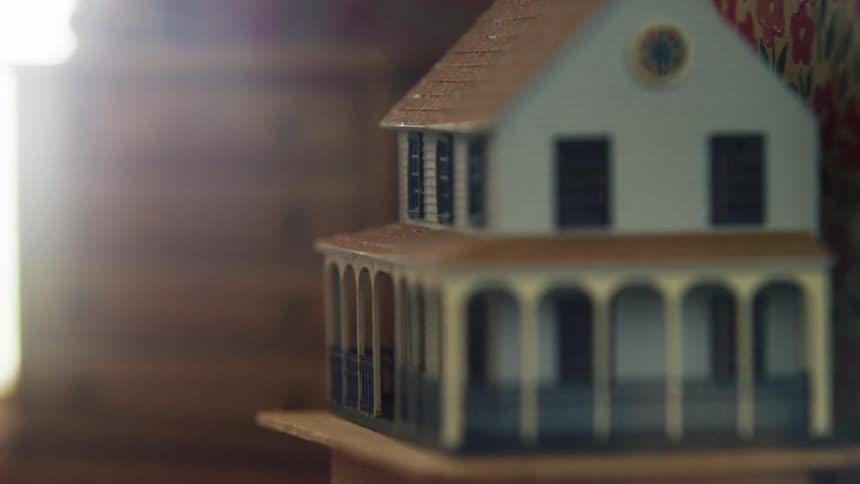 Doll house on the edge of a table in a room