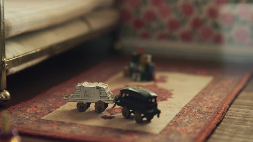 Toys sit on an oriental rug next to a bed