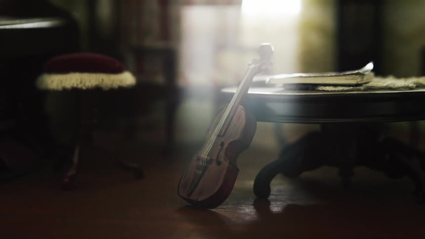 Light flows into room to shine on violin resting against table near piano