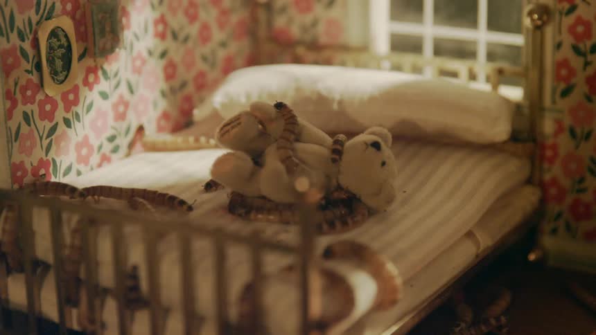 Surreal footage of giant worms crawling on a bed over a stuffed bear