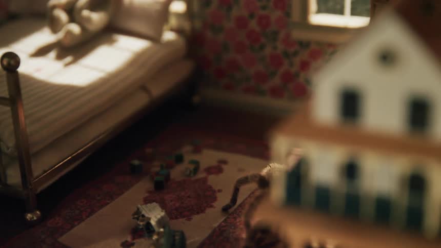 Large tarantula walks through a miniature bedroom and maneuvers around a table leg while a light swirls around outside a window