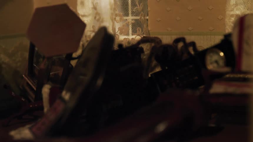 Tarantula climbs over dollhouse miniatures strewn through miniature room