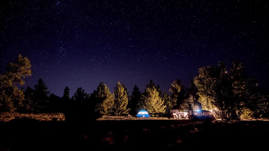 Tent and camper at night with a police car with lights illuminated