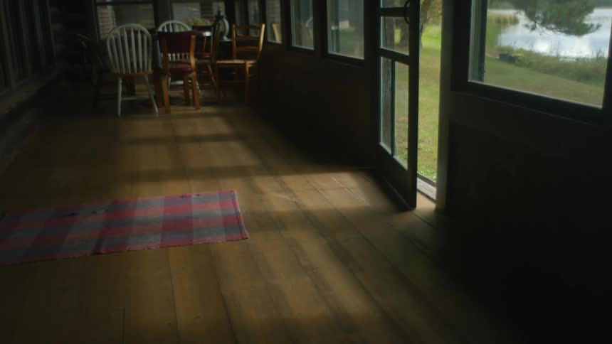 Inside of a dark house with chairs and a slightly opened front door