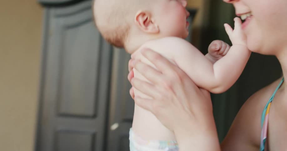 A woman picks up an infant from where it was lying on the couch