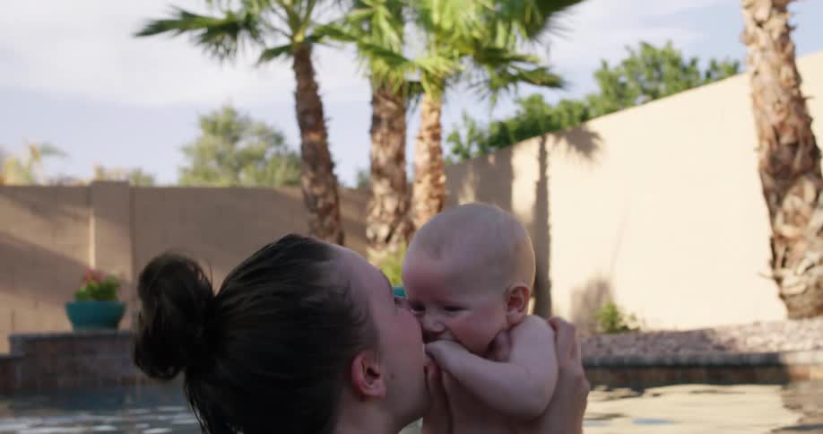 A mother playing with her baby in the water in a pool
