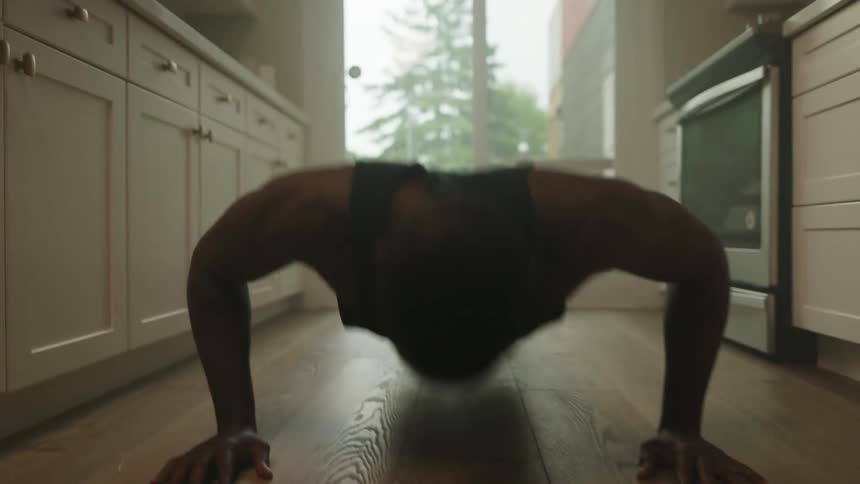 A young man doing push ups in his kitchen