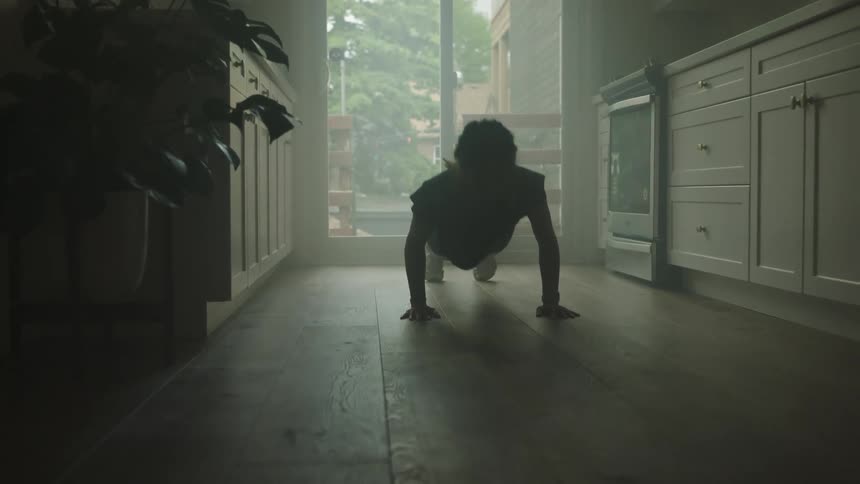 A woman gets down on her kitchen floor to do pushups