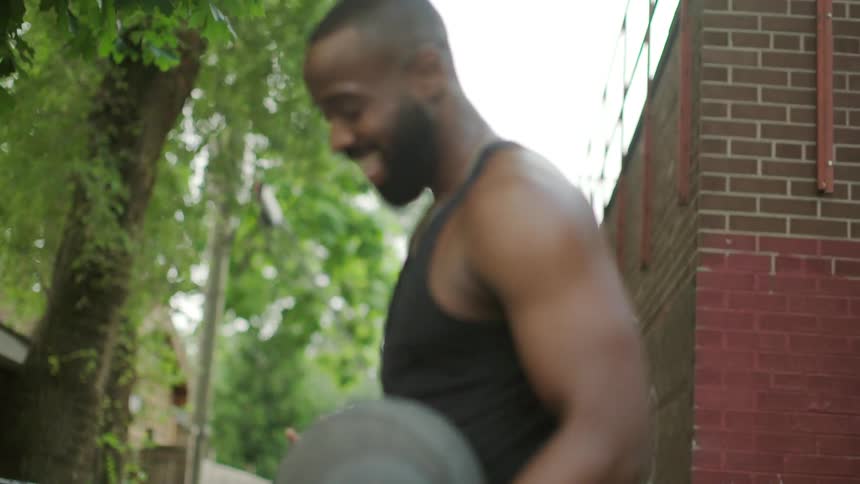 A man holding a basketball passes a woman and they high five outside in daylight