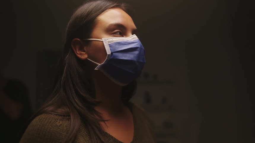 A woman is standing while wearing a mask on her face