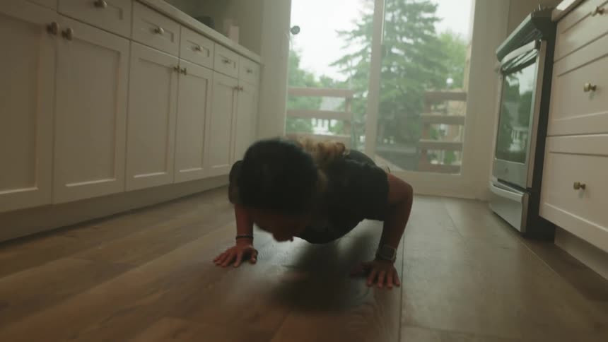 Woman does push ups on wooden floor in galley kitchen near doors