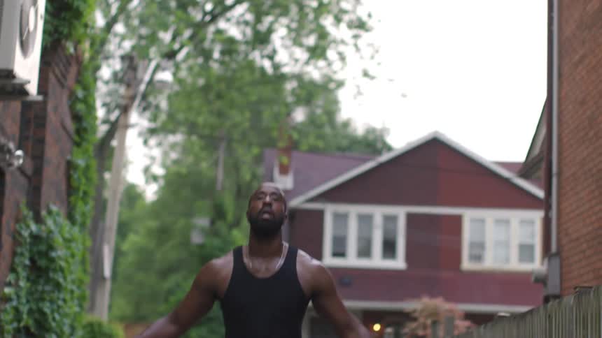 A man works out in his yard by jumping up and down and waving his arms
