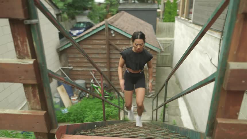 Woman sprinting up a flight of stairs in a backyard