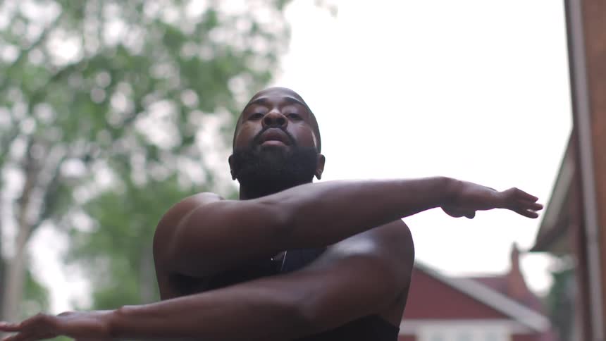 Man standing outside in front of some homes stretching his arms