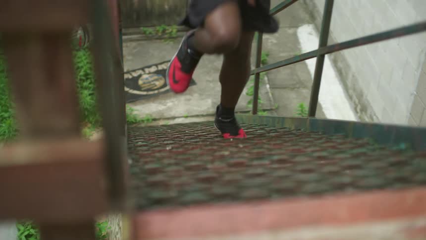 A person running upstairs wearing sneakers with a wall in the background