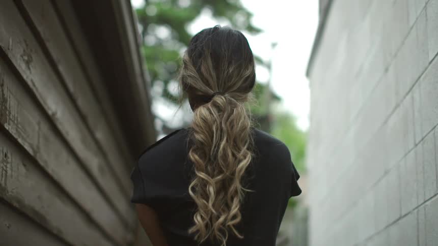 A female walks through an alley while swinging her arms