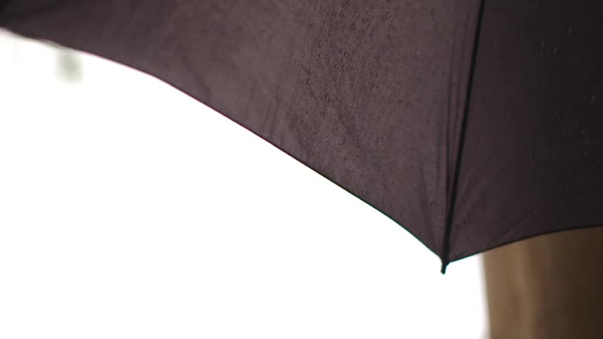A black umbrella with rain hitting in from the opposite side