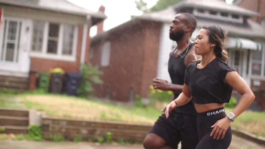 Muscular man with a beard and asian woman run down as the rain was falling heavily