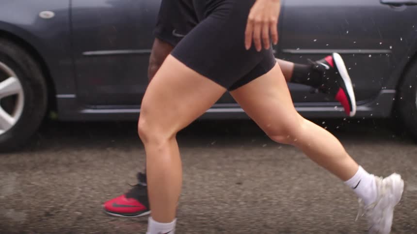 A man and woman run in unison down a wet road in the rain