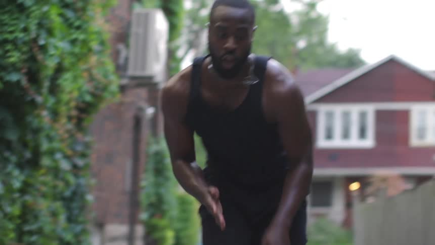A man does cardio exercises in an alleyway in a residential neighborhood during the day