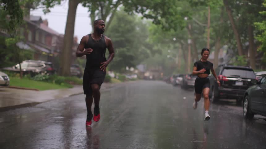 Man and woman run down the street as it rains