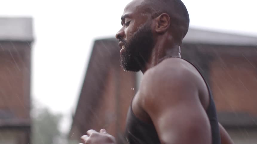 Muscular man with a beard and asian woman run down as the rain was falling heavily