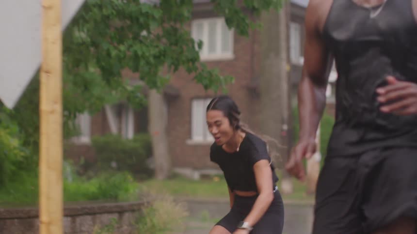 Man and a woman in workout clothes running in on a sidewalk in the rain