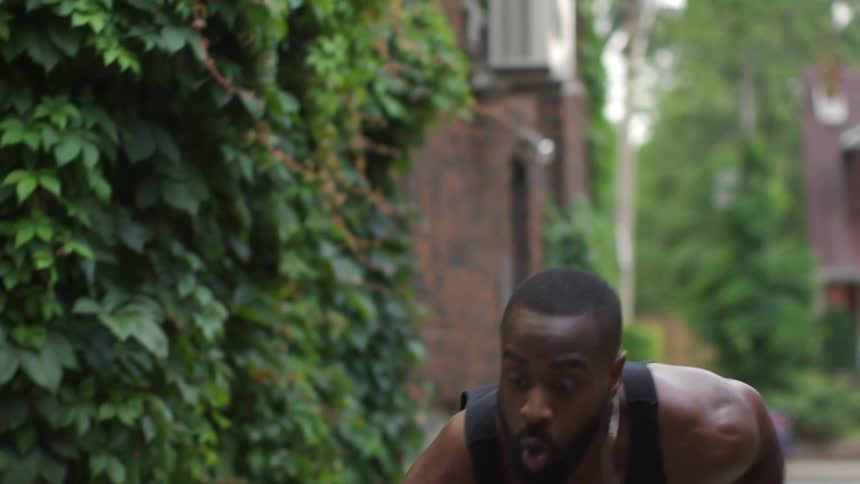 Man performing explosive exercise movements in an alley in a neighborhood