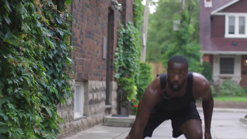 A black man is exercising in an alley