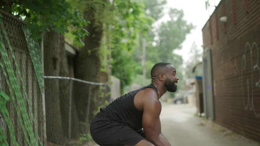 A man and a woman throw a medicine ball back and forth while working out in an alley