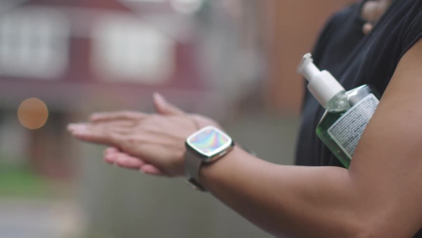 Man passes a bottle of hand sanitizer to a woman and woman uses it to clean her hand