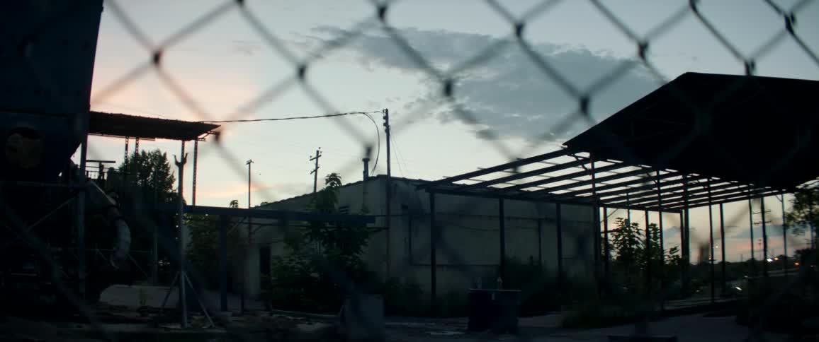 Chain link fence surrounds building as traffic passes nearby