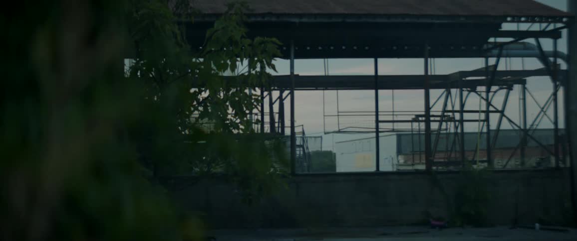The frame for a large building under construction sits near a highway in a rural area
