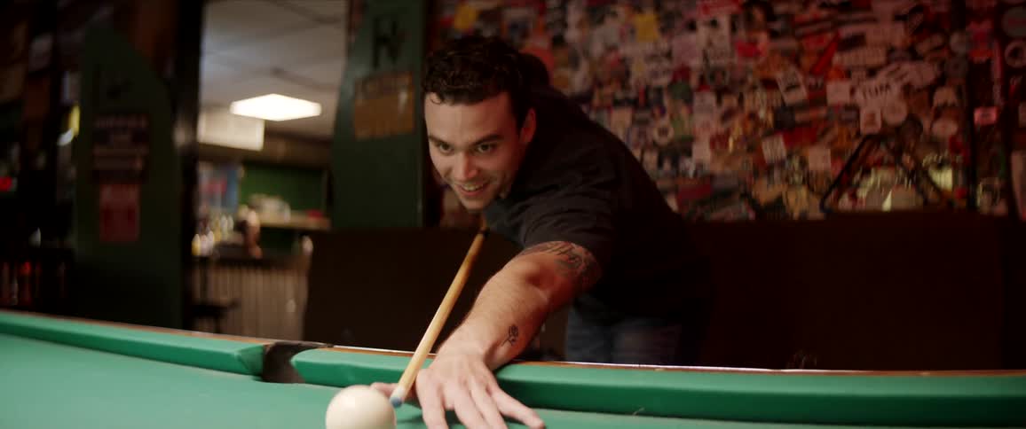 A man cheers after taking a shot while playing pool in a bar